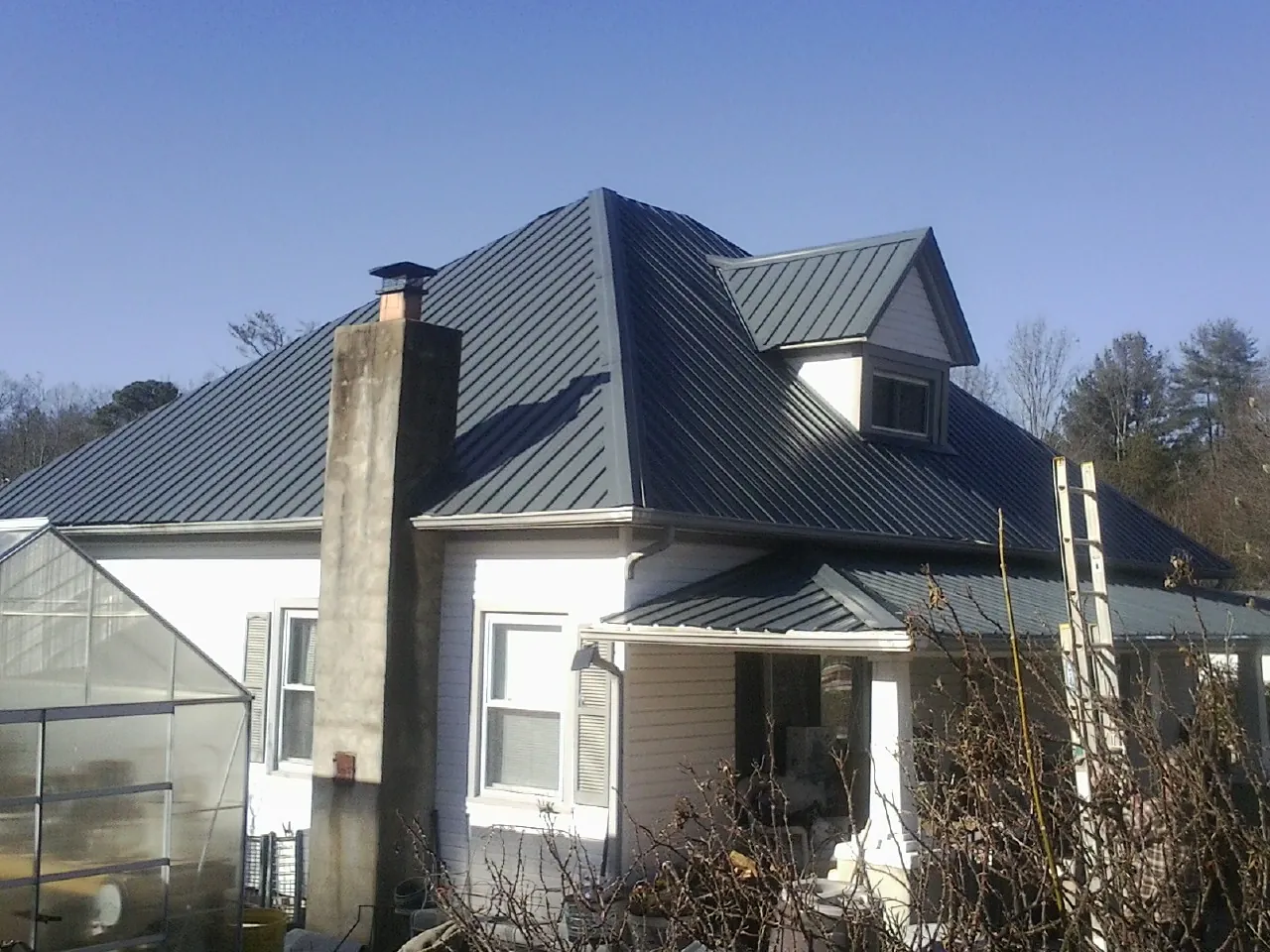 Dark blue standing seam metal roof on a white farmhouse with dormer — Slate & Tile Roof Repair by Roofing Brothers in Edmonton