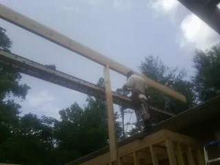 Carpenter setting a ridge beam over a new addition frame — Ice Dam Removal by Roofing Brothers in Edmonton