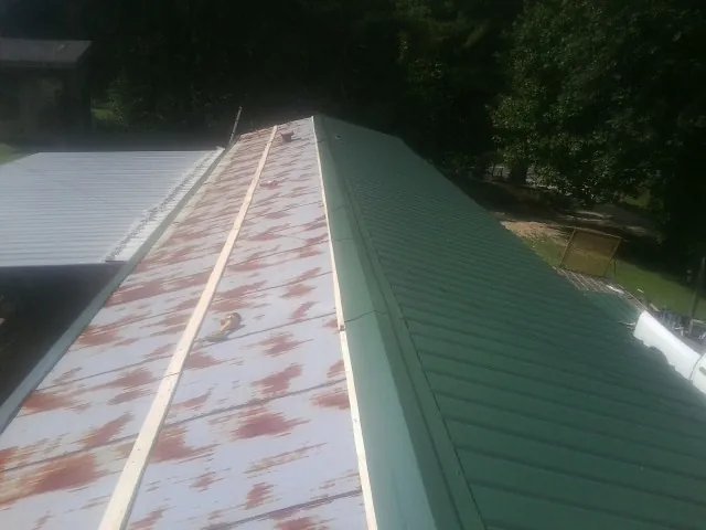 Old rusted panels beside newly installed green metal roofing — Wind Damage Roof Repair by Roofing Brothers in Edmonton
