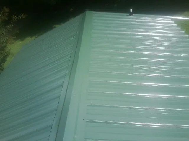 New green metal panels meeting at the ridge of a roof — Flat Roof Repair work by our crew in Edmonton
