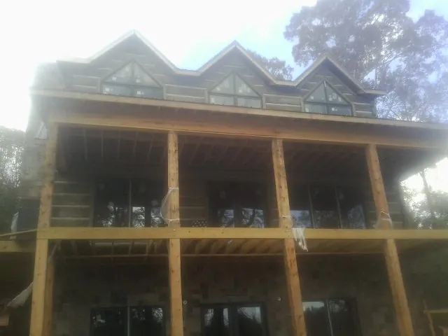 Dormers and porch framing on a large log home under construction — Roof Coating work by our crew in Edmonton