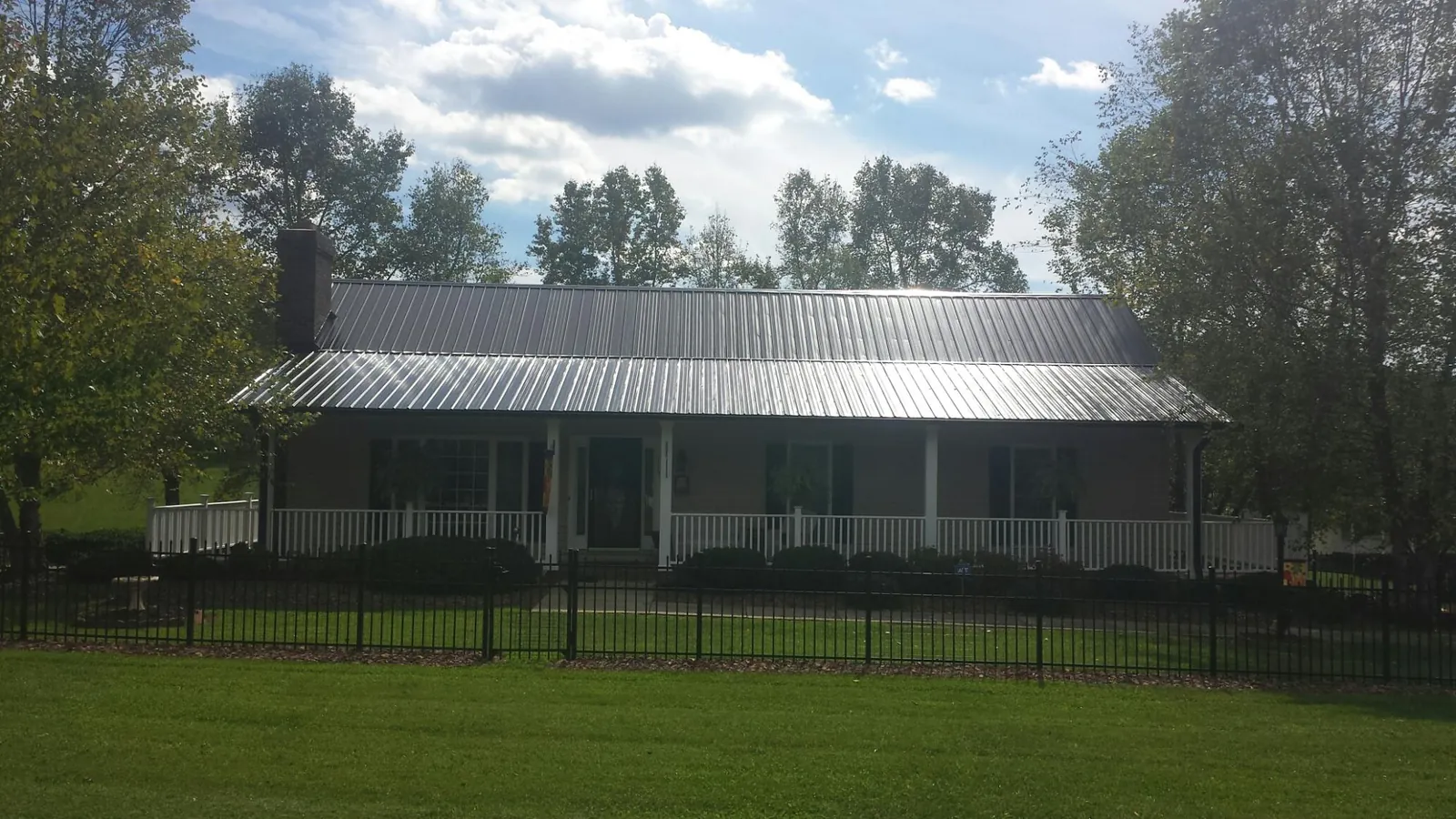 Gray metal roof on a brick ranch with a full width front porch — Gutter Guard Installation work by our crew in Edmonton