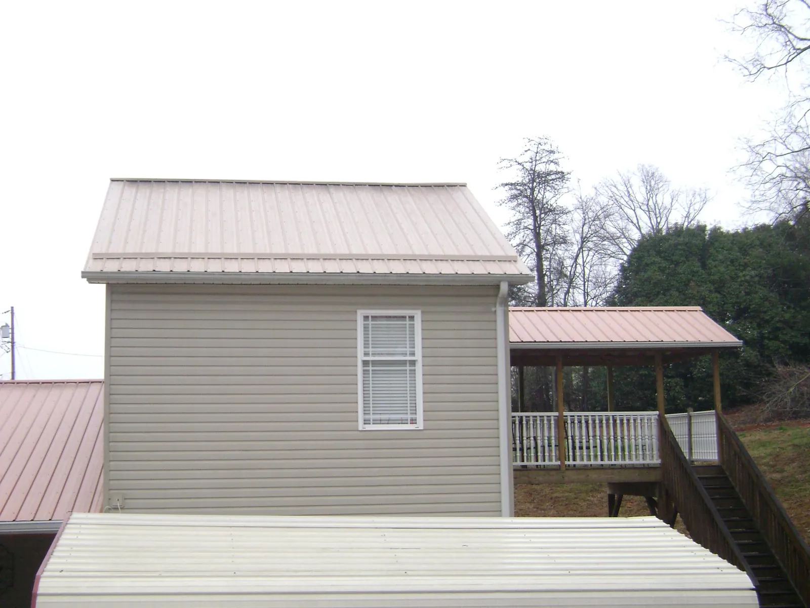 Tan metal roofs on a two story addition and attached porch, from a Roof Replacement job in Edmonton