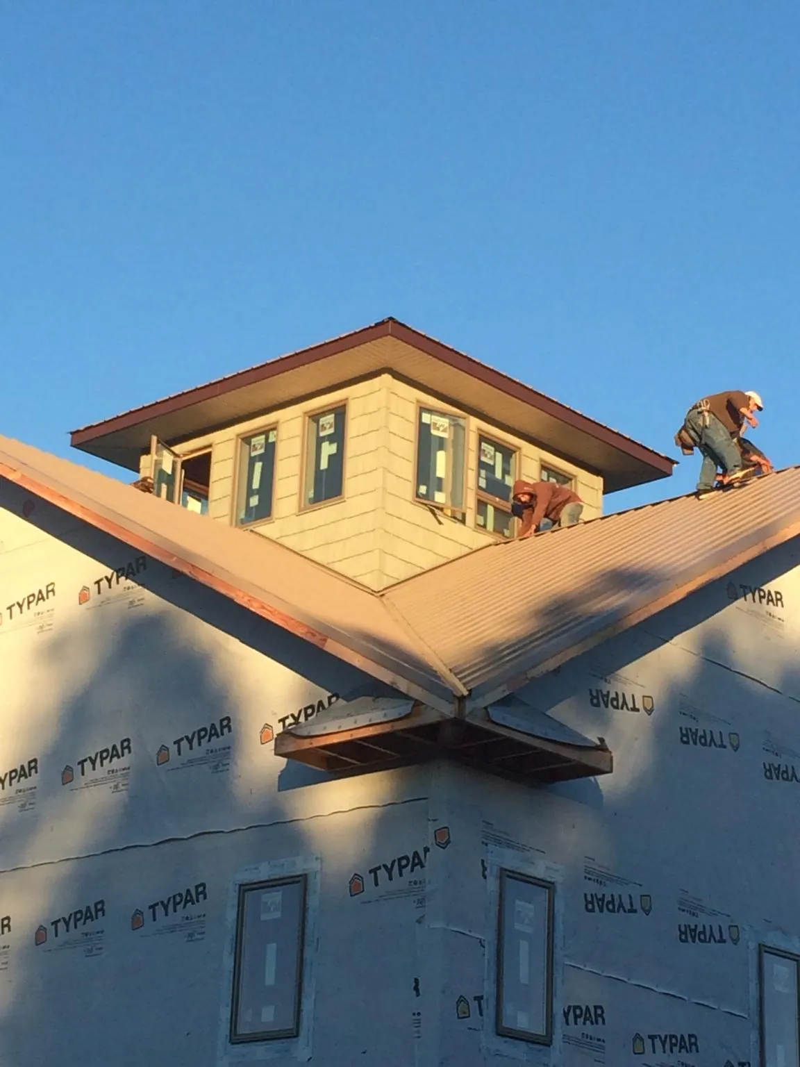 Roofers working around a rooftop cupola on a new metal roof at sunset — Roof Waterproofing in Edmonton by Roofing Brothers